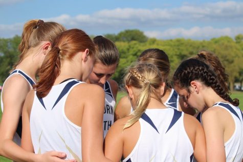 In this together: Varsity girls’ cross country huddles up before a run.  The team supports each other on and off the course, as they help motivate each other. 