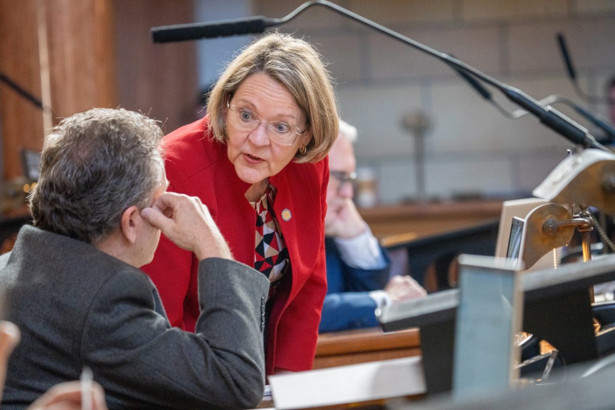 State Sen. Jane Raybould of Lincoln talks with State Sen. Stan Clouse of Kearney before debate on her priority bill to amend the voter-approved annual increases to the state's minimum wage. March 31, 2025. (Zach Wendling/Nebraska Examiner)