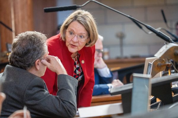 State Sen. Jane Raybould of Lincoln talks with State Sen. Stan Clouse of Kearney before debate on her priority bill to amend the voter-approved annual increases to the state's minimum wage. March 31, 2025. (Zach Wendling/Nebraska Examiner)